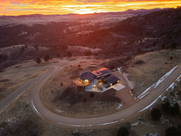 Aerial drone photo captured by Odrix Media showcasing a custom-built home at sunset, surrounded by winding roads and scenic hills, highlighting professional Drone Photography Services for a custom home builder.