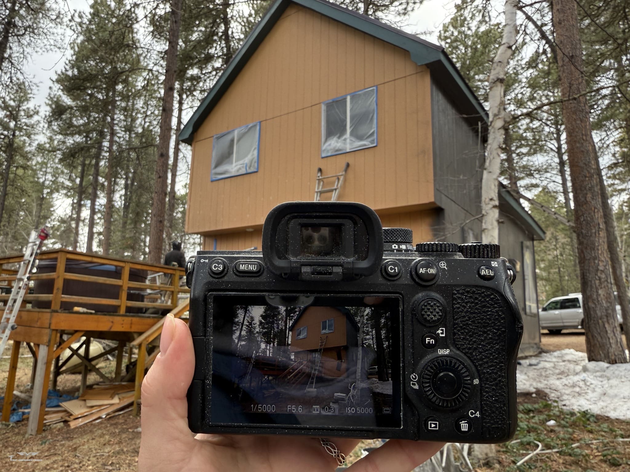 Odrix Media capturing a corporate branding photography shoot with a digital camera in front of a wood-paneled cabin in Deer Mountain Village, Lead, South Dakota.